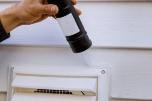 Applying silicone on installing side fan for laundry fan outside siding trim